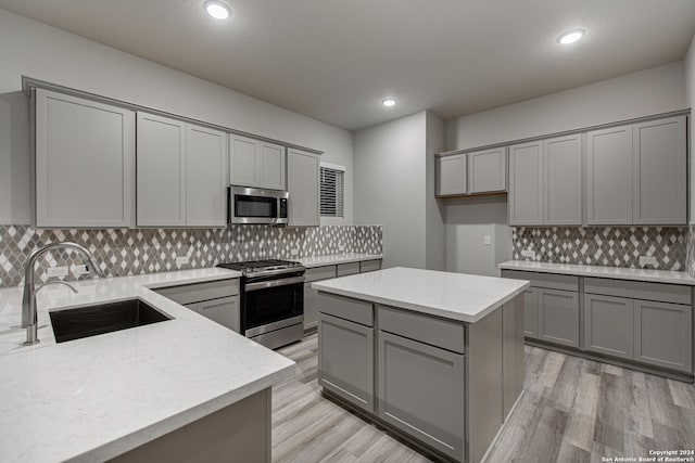 kitchen featuring decorative backsplash, stainless steel appliances, a kitchen island, and gray cabinetry