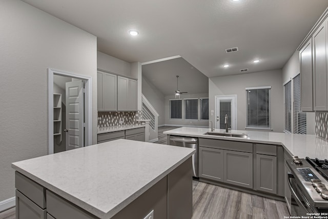 kitchen with light hardwood / wood-style flooring, ceiling fan, stainless steel appliances, tasteful backsplash, and sink