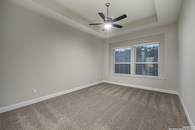 carpeted spare room with ceiling fan and a raised ceiling