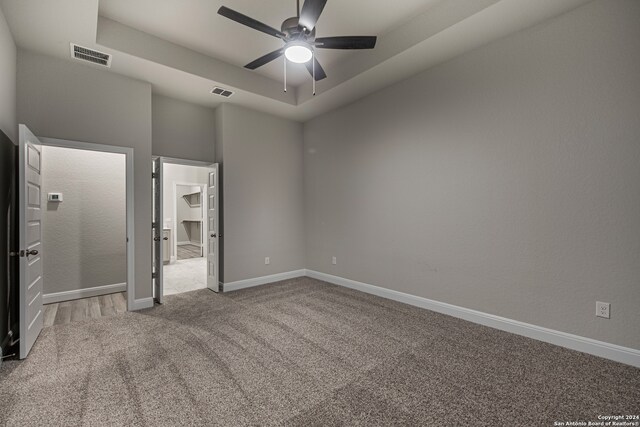 unfurnished bedroom with ceiling fan, a towering ceiling, a spacious closet, carpet flooring, and a closet