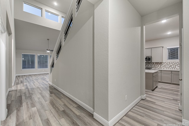 hall with a high ceiling and light hardwood / wood-style floors