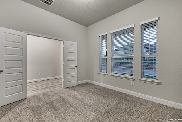 unfurnished bedroom with a textured ceiling and light carpet