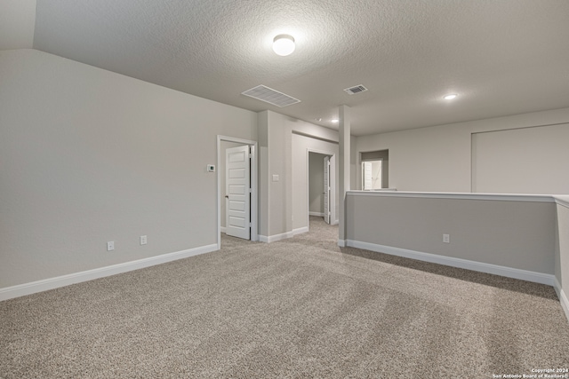 carpeted spare room featuring lofted ceiling and a textured ceiling