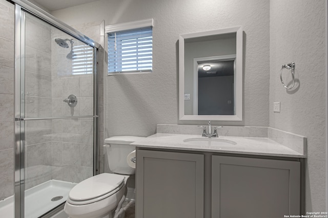 bathroom with a shower with door, vanity, and toilet