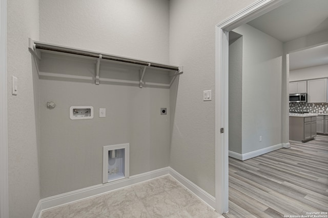 washroom featuring electric dryer hookup, gas dryer hookup, hookup for a washing machine, and light hardwood / wood-style floors