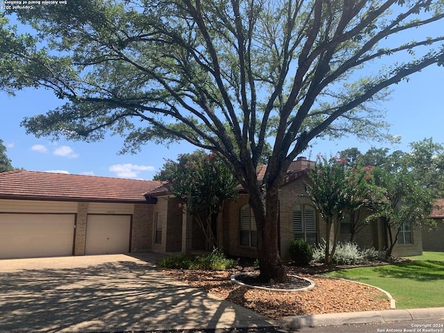 single story home with driveway, brick siding, a front lawn, and an attached garage