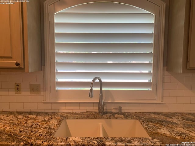 details with backsplash, dark stone countertops, and a sink