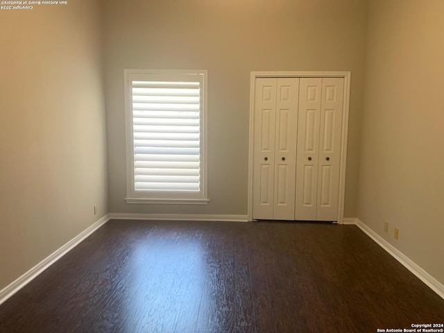 unfurnished bedroom with a closet, baseboards, and wood finished floors