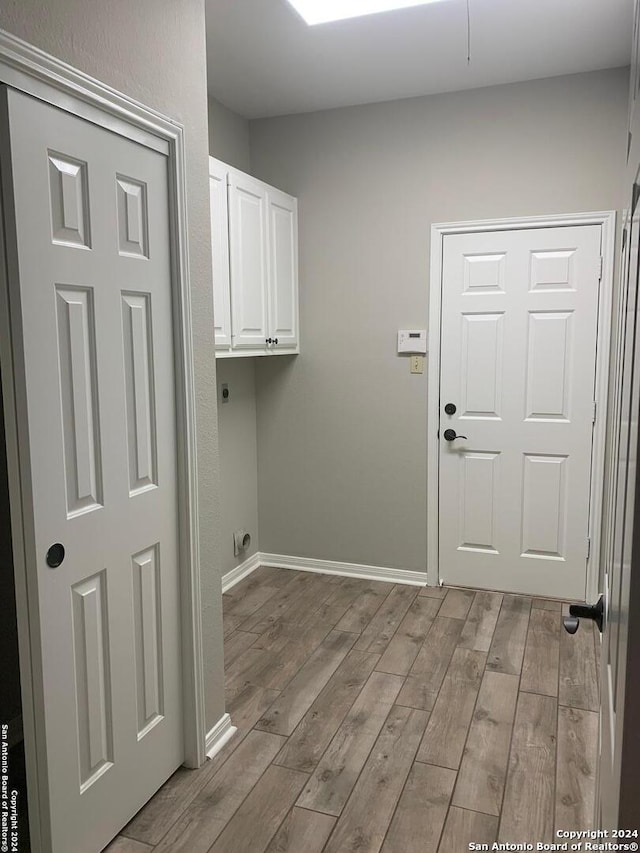 washroom featuring hookup for an electric dryer, cabinet space, baseboards, and wood finished floors