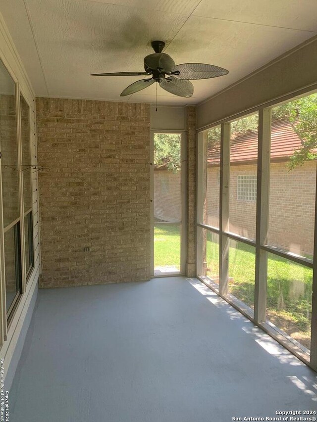 unfurnished sunroom with ceiling fan