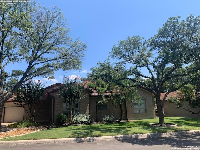 view of front facade featuring an attached garage, a front lawn, and brick siding