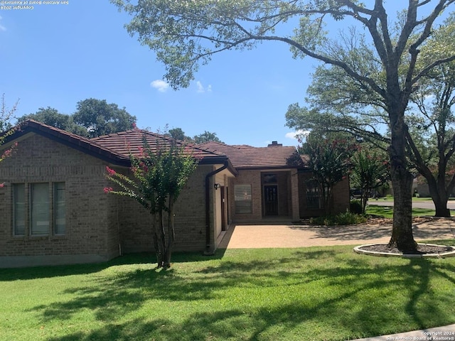 exterior space with a front yard, a tile roof, and brick siding