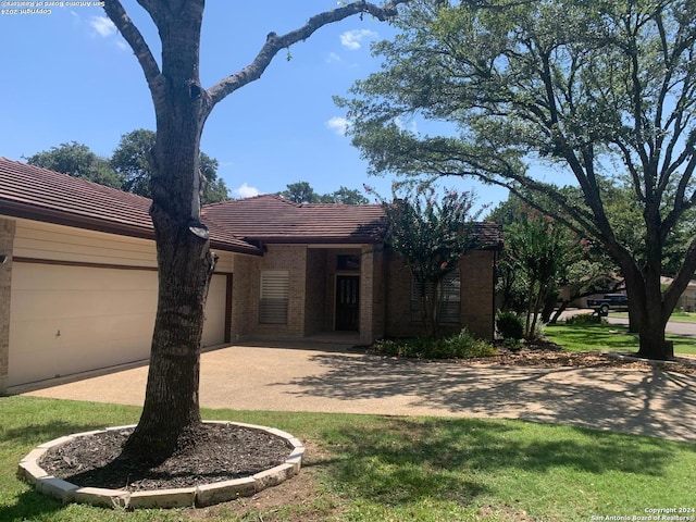 ranch-style house featuring an attached garage, a tile roof, and brick siding