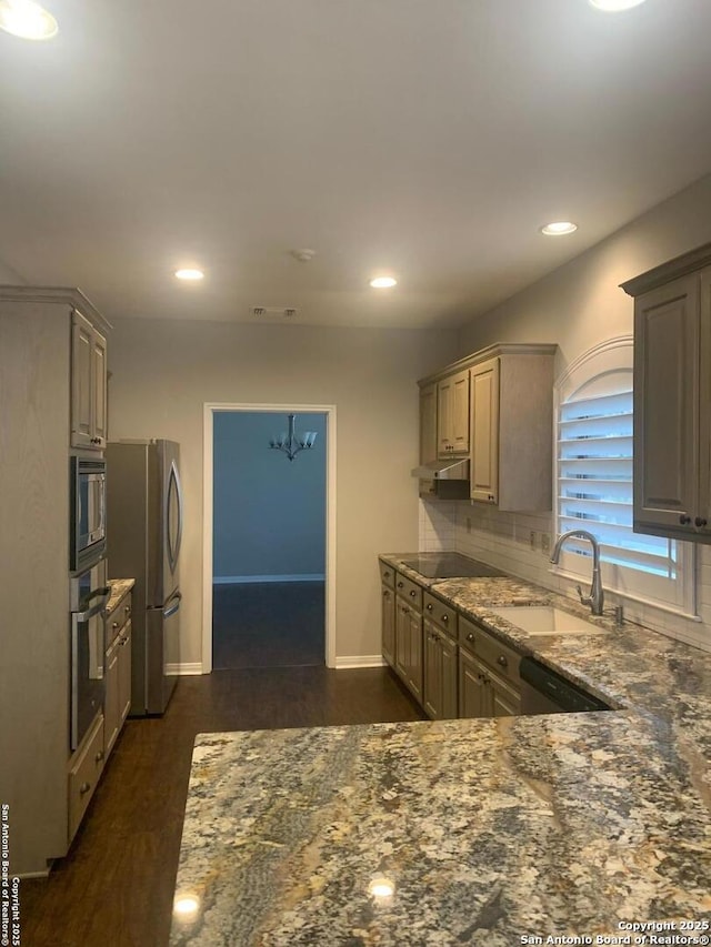 kitchen featuring stainless steel appliances, visible vents, decorative backsplash, a sink, and dark stone countertops