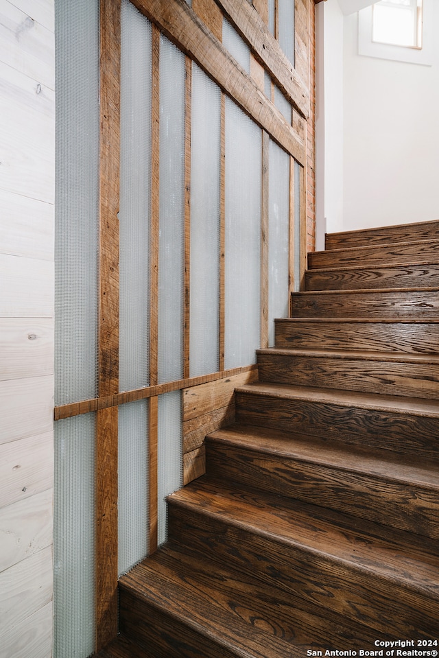 staircase featuring wood walls