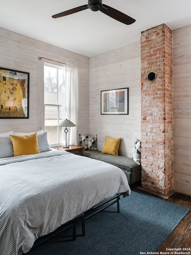 bedroom featuring ceiling fan, wooden walls, and dark hardwood / wood-style floors