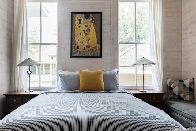 bedroom featuring multiple windows and wooden walls