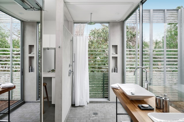 bathroom featuring a wealth of natural light, double sink, and floor to ceiling windows