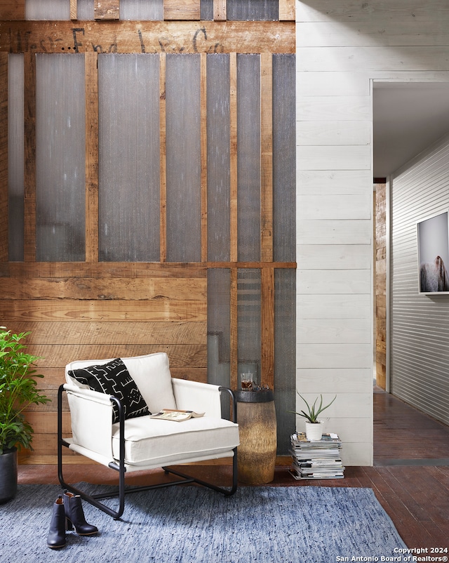 sitting room with dark wood-type flooring and wooden walls