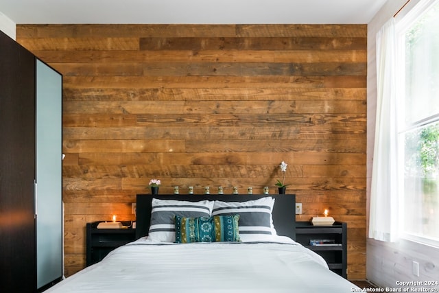 bedroom with multiple windows and wooden walls