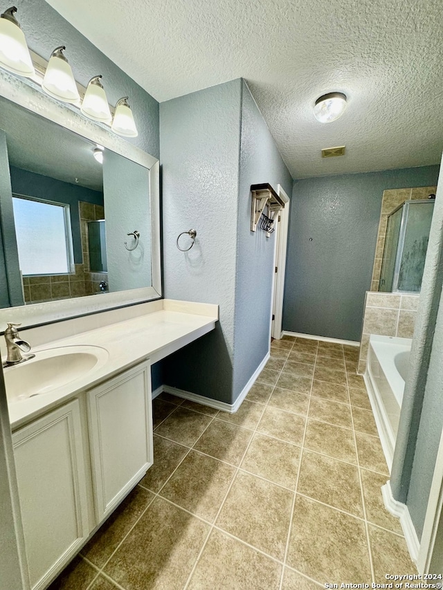 bathroom with vanity, a textured ceiling, a bathing tub, and tile patterned flooring