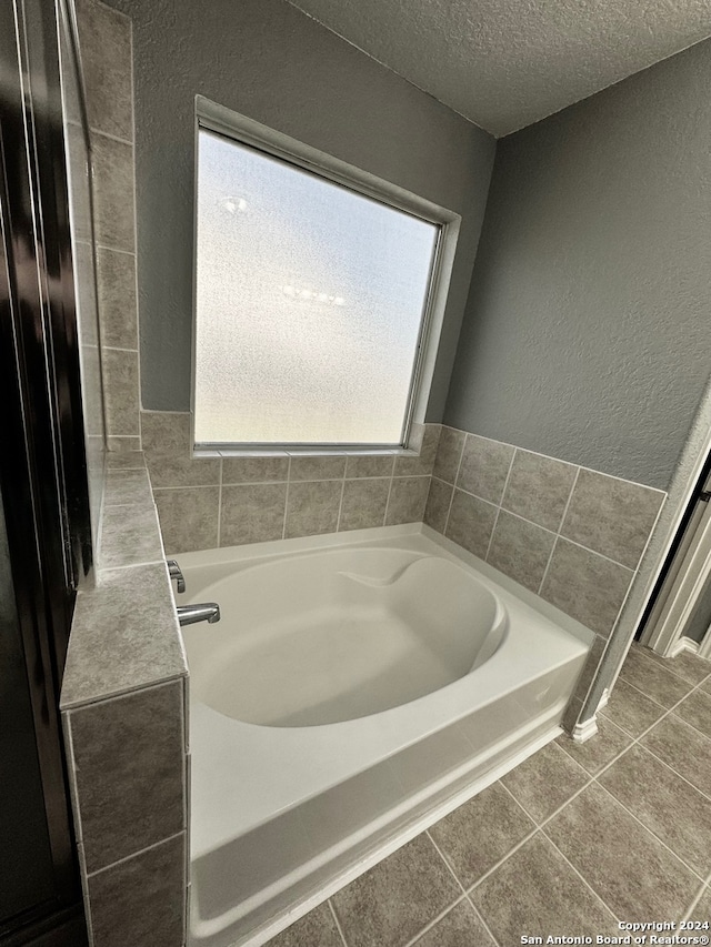 bathroom with a textured ceiling, a washtub, and tile patterned floors