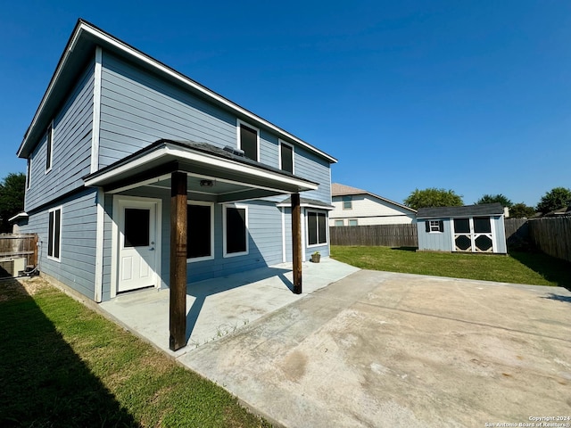 rear view of house with a patio area, a yard, and a storage shed