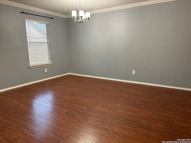 spare room featuring a notable chandelier, ornamental molding, and dark hardwood / wood-style flooring