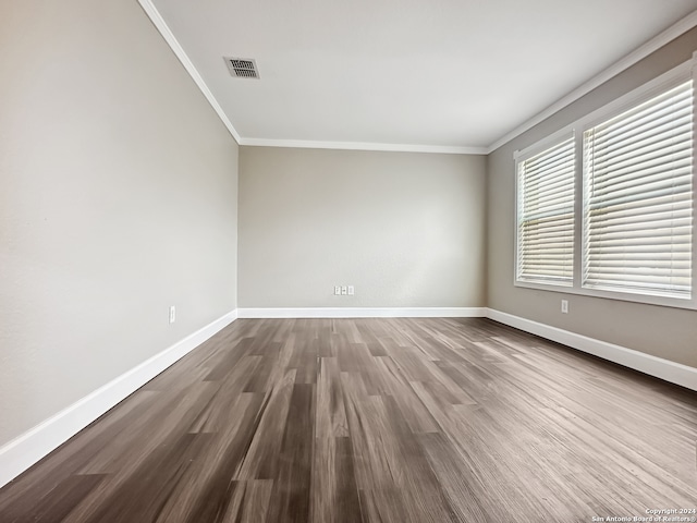 empty room with hardwood / wood-style flooring and ornamental molding