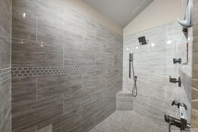 bathroom with lofted ceiling and a tile shower