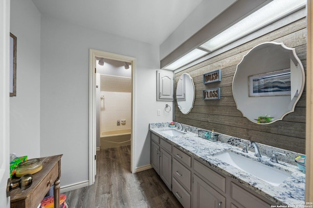 bathroom with hardwood / wood-style flooring, vanity, and washtub / shower combination