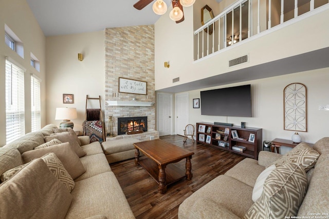 living room with ceiling fan, a fireplace, dark hardwood / wood-style floors, and a high ceiling