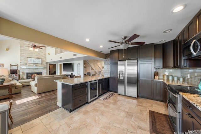 kitchen featuring light stone counters, appliances with stainless steel finishes, beverage cooler, and dark brown cabinets