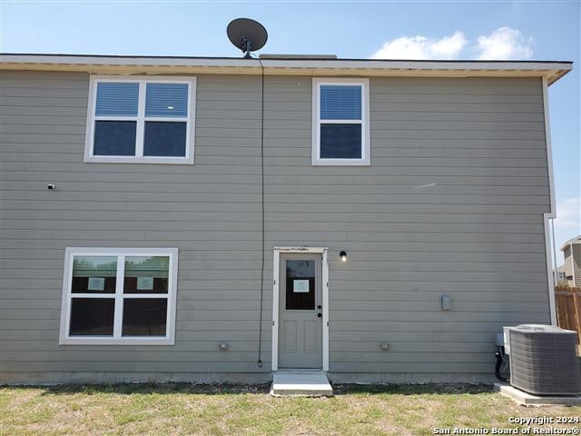 rear view of property featuring central AC and a yard