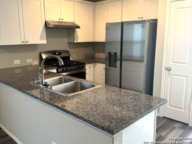 kitchen with appliances with stainless steel finishes, kitchen peninsula, sink, and white cabinets