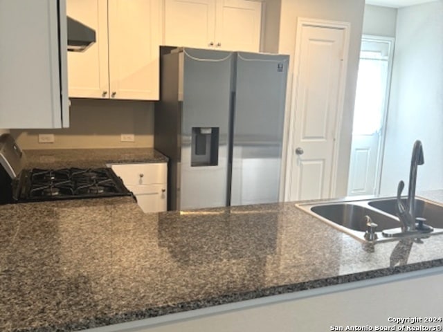 kitchen featuring white cabinets, dark stone countertops, sink, stainless steel fridge, and stove