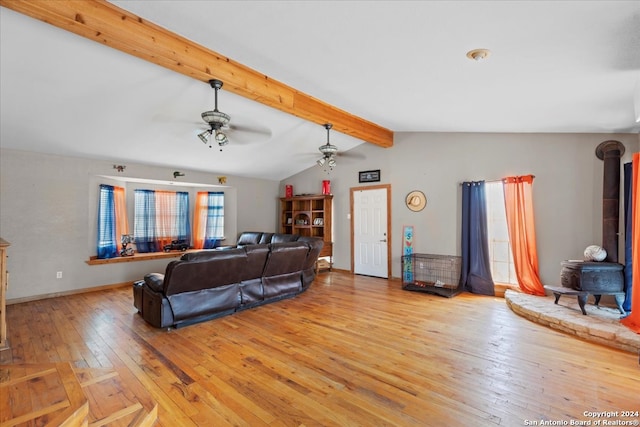 living room featuring ceiling fan, light hardwood / wood-style flooring, lofted ceiling with beams, and a wood stove