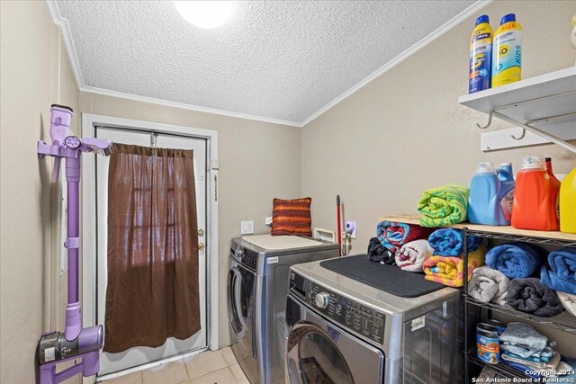 laundry room featuring washing machine and dryer, light tile patterned flooring, ornamental molding, and a textured ceiling