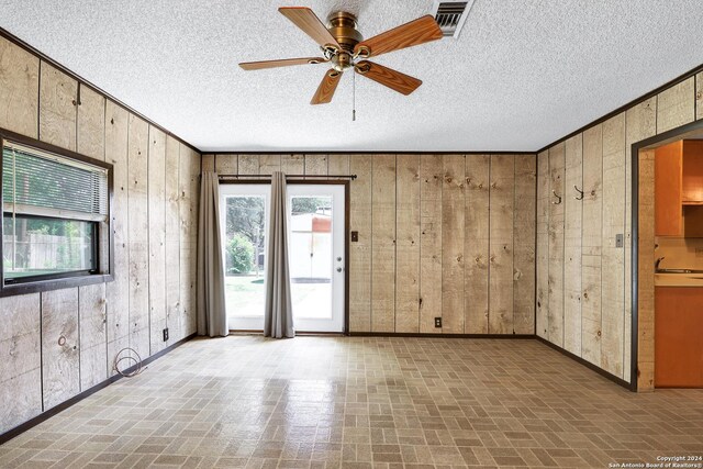 spare room featuring ceiling fan, wood walls, sink, and a textured ceiling