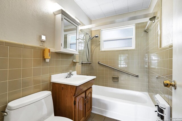 full bathroom featuring toilet, tile walls, tiled shower / bath, tile patterned floors, and vanity