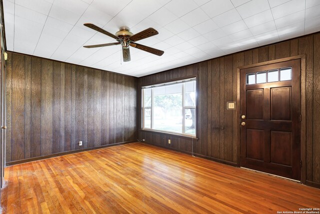 entryway featuring ceiling fan, wood walls, and light hardwood / wood-style floors