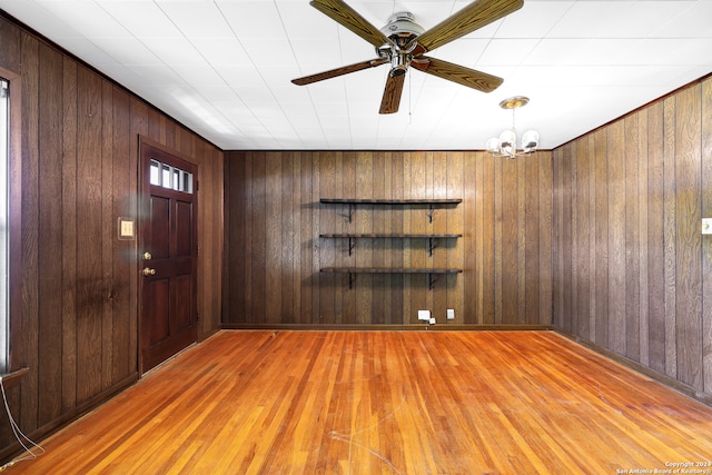 entrance foyer featuring wood-type flooring, ceiling fan with notable chandelier, and wooden walls