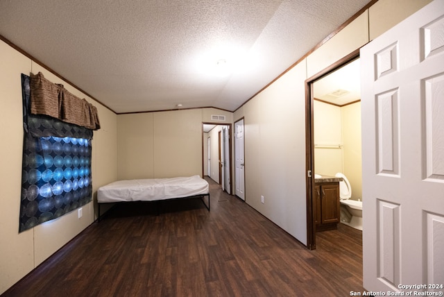 unfurnished bedroom featuring ensuite bath, dark hardwood / wood-style flooring, a textured ceiling, and vaulted ceiling