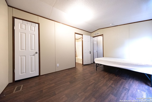 unfurnished bedroom featuring a textured ceiling, dark hardwood / wood-style flooring, and vaulted ceiling