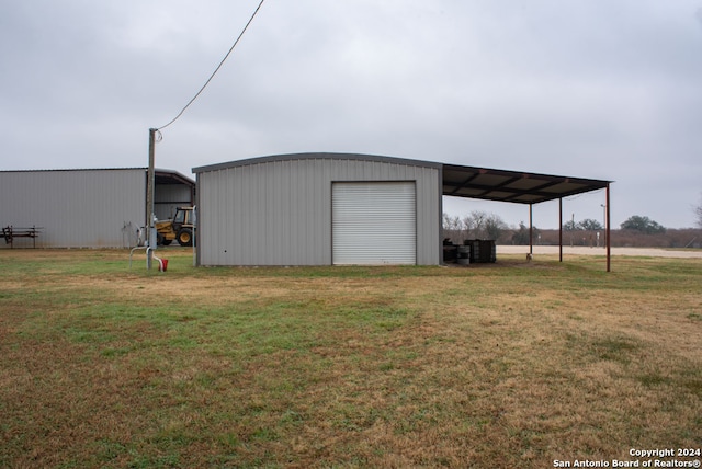 view of outdoor structure featuring a carport, a lawn, and a garage