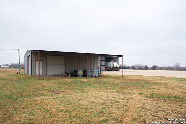 view of outbuilding featuring a lawn, a carport, and a garage