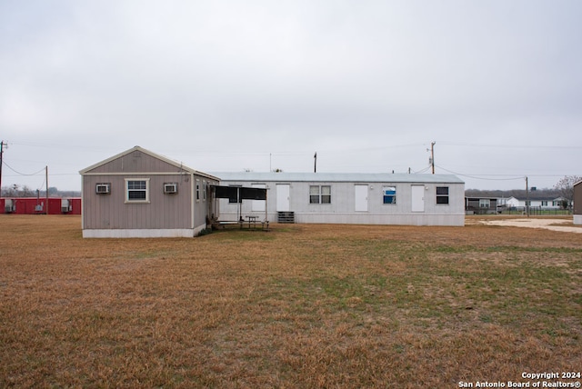 rear view of property with an outdoor structure, cooling unit, a wall mounted AC, and a lawn