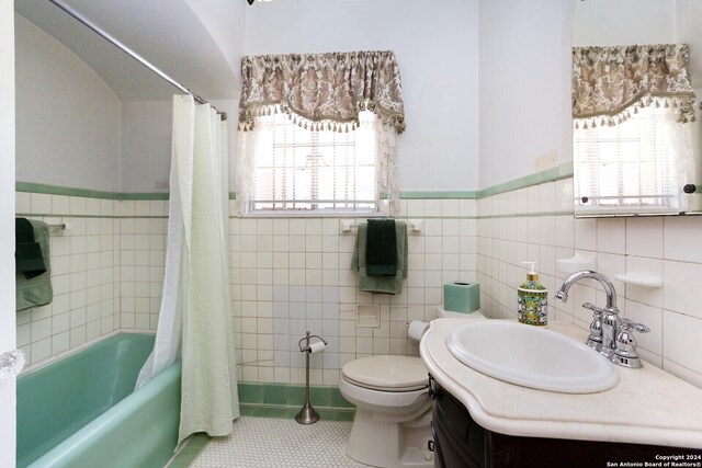 full bathroom with toilet, tile patterned floors, tile walls, shower / bath combination with curtain, and vanity