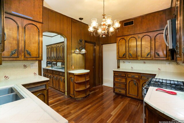 kitchen featuring tile countertops, a notable chandelier, hanging light fixtures, backsplash, and dark hardwood / wood-style floors