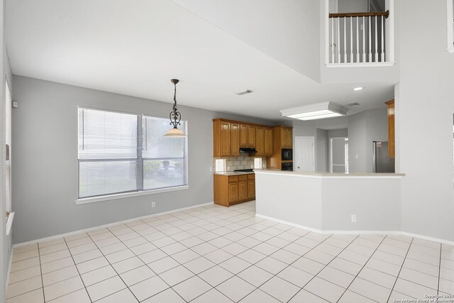 kitchen with tasteful backsplash, black microwave, hanging light fixtures, stainless steel refrigerator, and light tile patterned floors